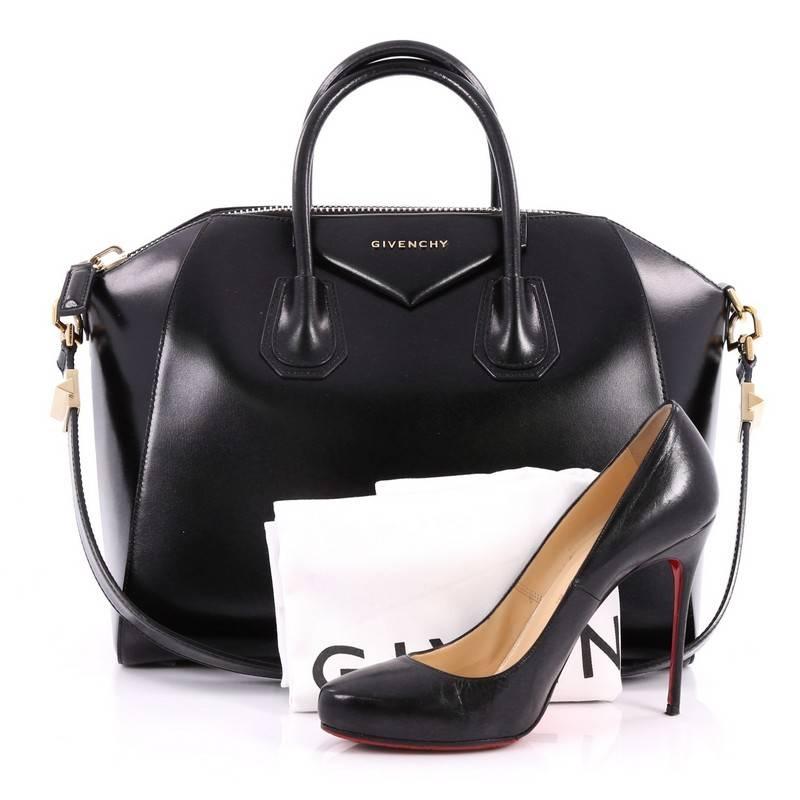 This authentic Givenchy Antigona Bag Glazed Leather Medium combines style and functionality all-in-one. Crafted from sleek black glazed leather, this structured handle bag features dual-rolled leather handle and gold-tone hardware accents. Its zip