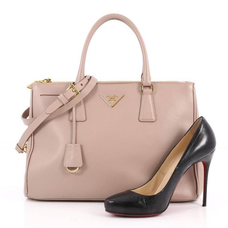 This authentic Prada Double Zip Lux Tote Saffiano Leather Small is the perfect bag to complete any outfit. Crafted from light pink saffiano leather, this boxy tote features side snap buttons, raised Prada logo, dual-rolled leather handles and