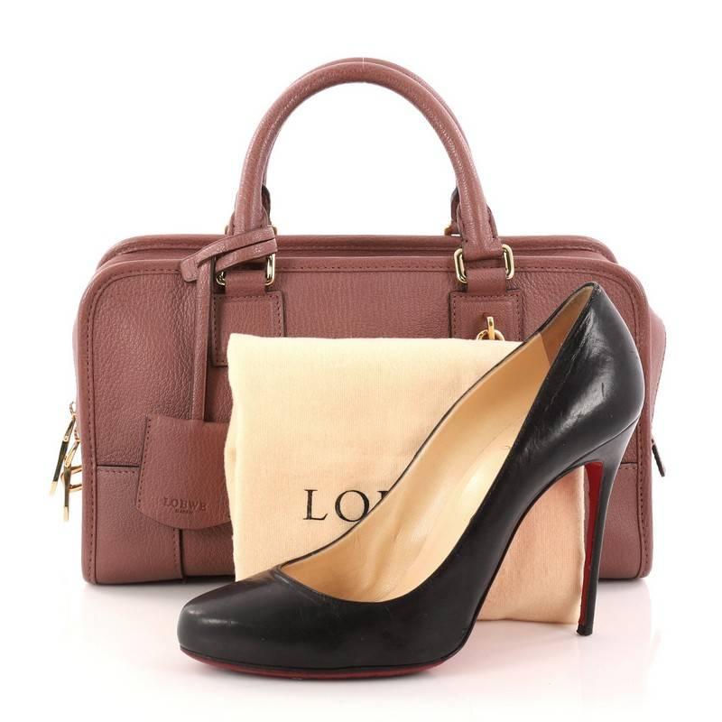 This authentic Loewe Amazona Bag Leather 28 is a perfect minimalist handbag for on-the-go fashionista. Crafted in dusty rose leather, this bag features dual-rolled leather handles, embossed logo at front, and gold-tone hardware accents. Its zip