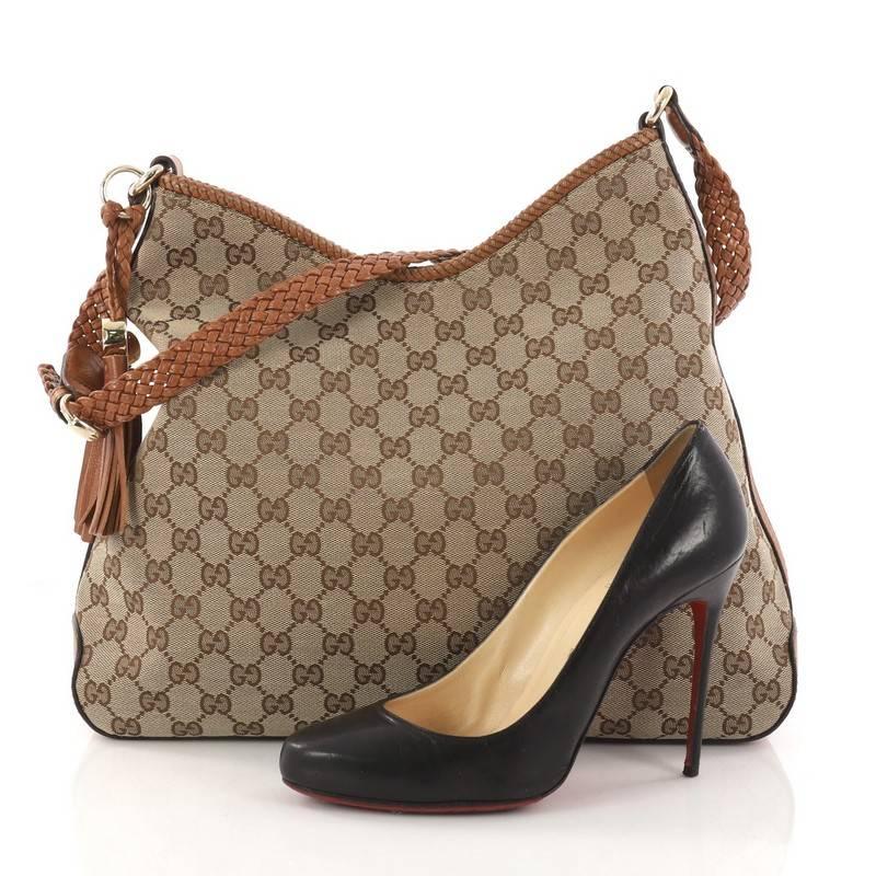 This authentic Gucci Bella Tote GG Canvas Medium is a classic piece ideal for casual wear. Crafted in brown GG canvas, this tote features braided leather handle, bamboo tassel charms, metallic silver leather trims, and gold-tone hardware accents.
