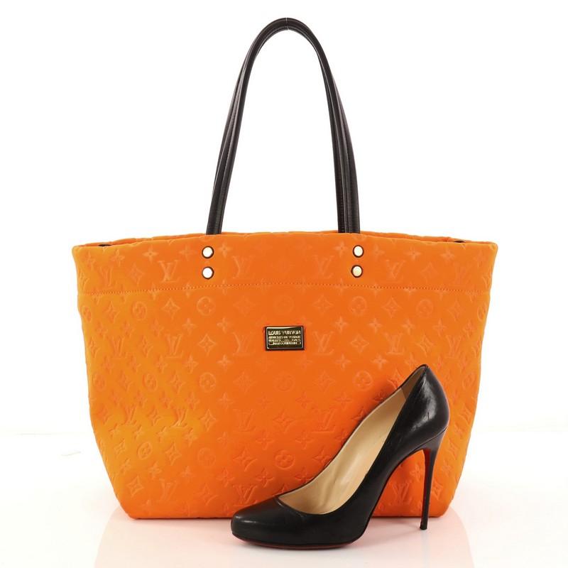 This authentic Louis Vuitton Scuba Tote Monogram Embossed Neoprene MM is a stylish and functional bag made for everyday use or weekend getaways. Crafted from eye-catching orange monogram embossed neoprene, this vibrant tote features smooth black