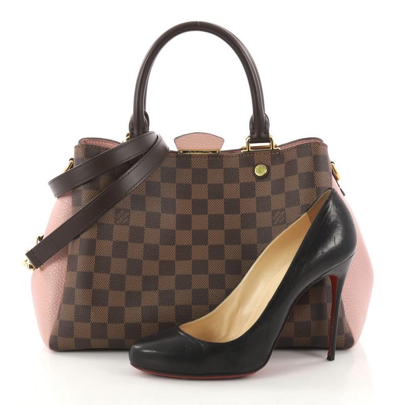 This authentic Louis Vuitton Brittany Handbag Damier from 2018 makes an elegant statement. Crafted from damier ebene coated canvas and pink cuir taurillon leather, this sophisticated bag features dual-rolled leather handles, smooth brown cowhide
