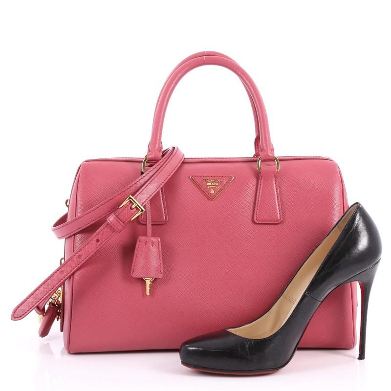 This authentic Prada Convertible Bowler Bag Saffiano Leather Medium exudes a stylish and industrial design made for everyday excursions. Crafted from pink saffiano leather, this structured bowler satchel features dual-rolled top handles, protective