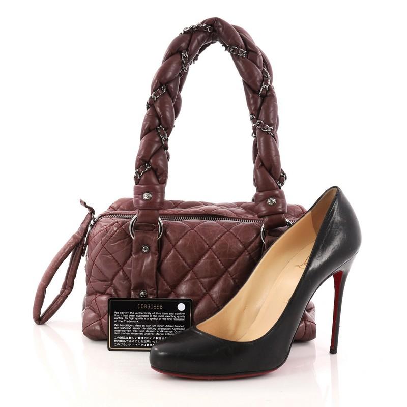 This authentic Chanel Lady Braid Bowler Bag Quilted Distressed Lambskin Small is perfect for the on-the-go fashionista. Constructed from burgundy diamond quilted leather, this petite tote features intertwined woven leather chain straps, side silver