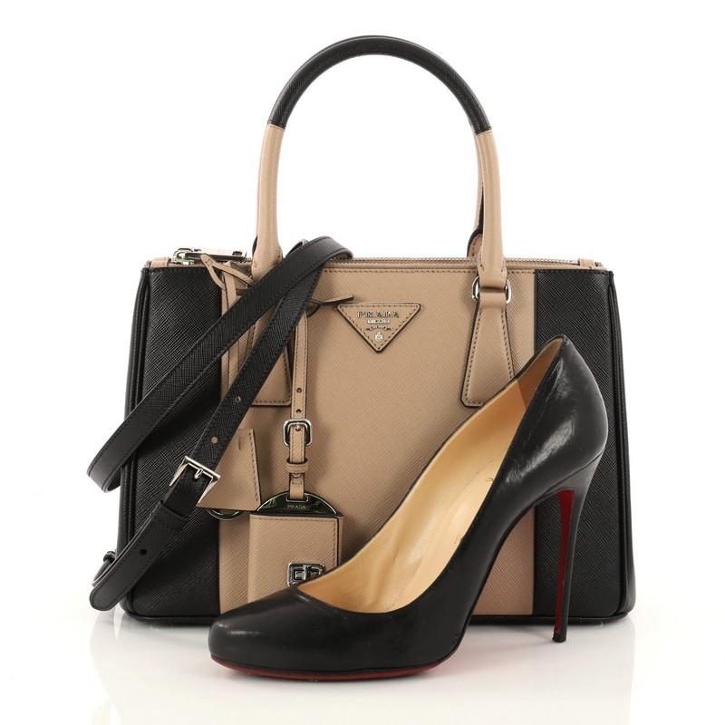 This authentic Prada Bicolor Double Zip Lux Tote Saffiano Leather Small is the perfect bag to complete any simple outfit. Crafted in light taupe and black saffiano leather, this elegant and chic bag features side snap buttons, raised Prada logo,