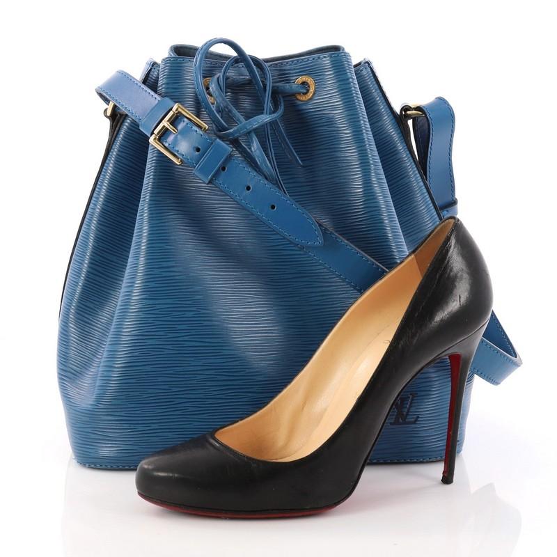 This authentic Louis Vuitton Petit Noe Handbag Epi Leather is a chic and iconic bag in the highly sought-after bucket style. Crafted from Louis Vuitton's blue Epi Leather, this bag features leather drawstrings, adjustable shoulder straps, subtle LV