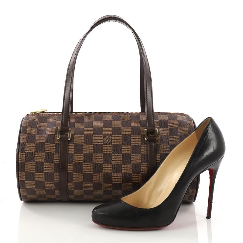 This authentic Louis Vuitton Papillon Handbag Damier 30 is one of Louis Vuitton's most iconic bags with its unique round shape that complements both dressy and casual looks. Crafted with damier ebene coated canvas and dark brown leather trims, this