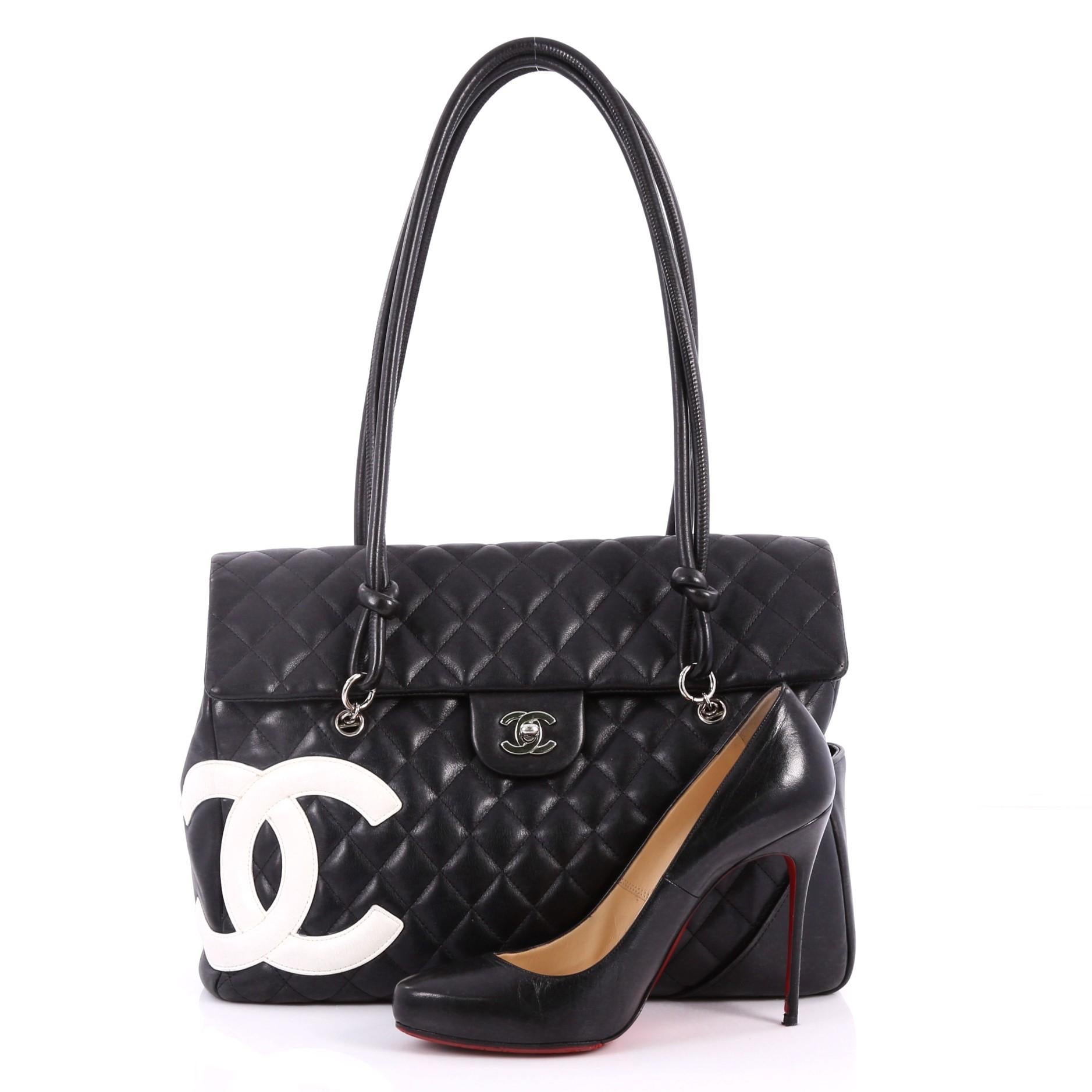 This authentic hard-to-find Chanel Cambon Flap Tote Quilted Leather Large is a stylish and functional accessory perfect for daily excursions. Crafted in black quilted leather, this tall tote features tall handles with knotted ends, signature white