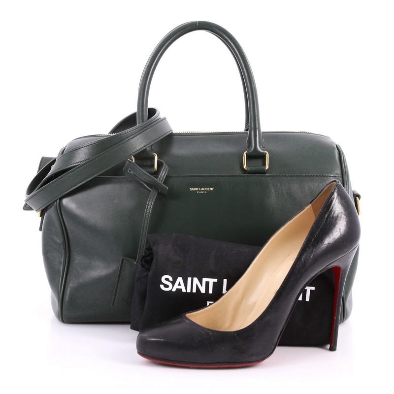 This authentic Saint Laurent Classic Duffle Bag Leather 6 is a modern and elegant duffle bag to travel with. Crafted in dark green leather, this alluring bag features dual-rolled leather handles, stamped Saint Laurent logo at the front, protective