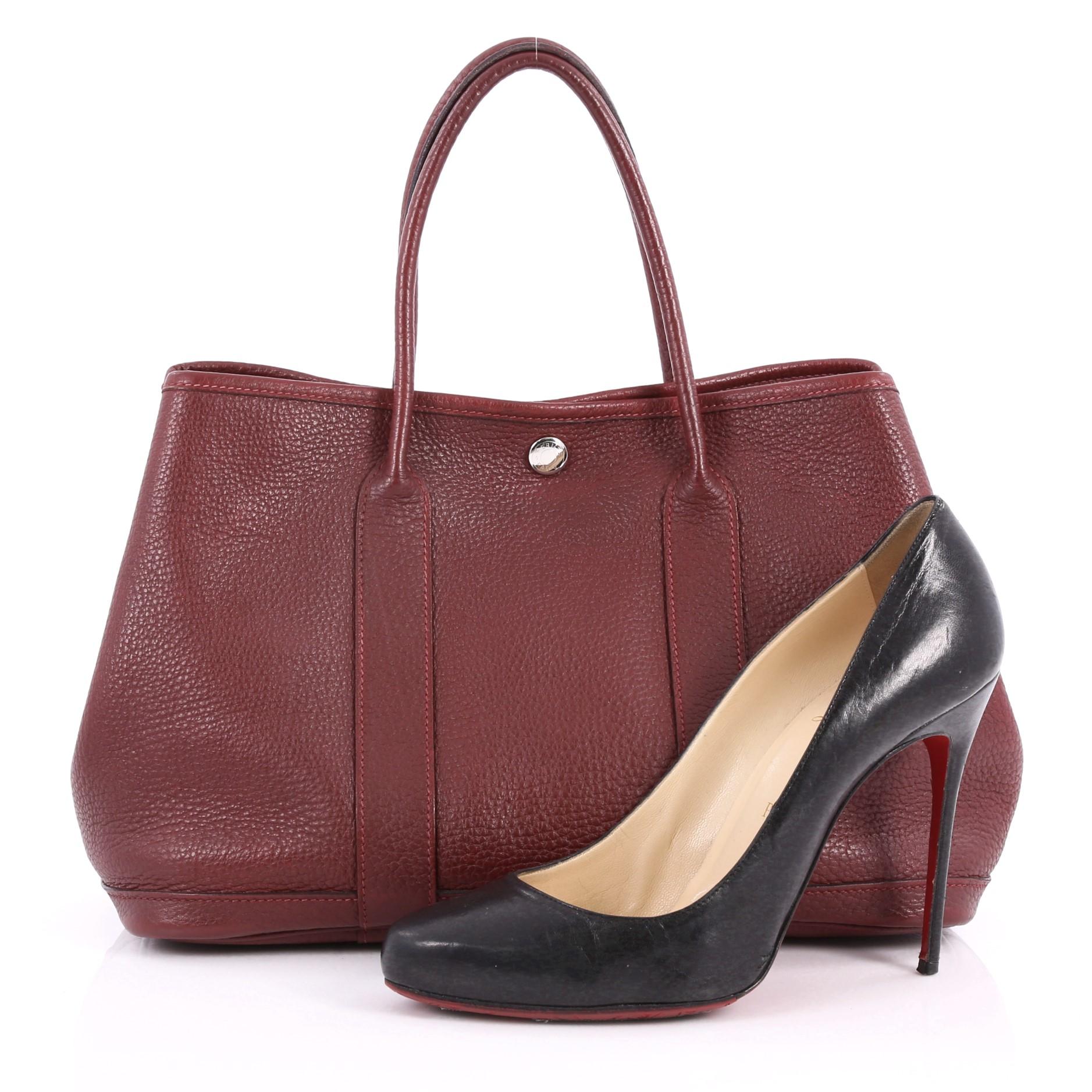 This authentic Hermes Garden Party Tote Leather 30 is an elegant and simple tote made for all seasons. Crafted from burgundy leather, this chic everyday tote features dual-rolled leather top handles, palladium button closure, side snap buttons and
