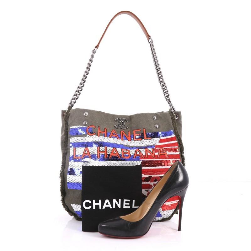 This authentic Chanel Cuba La Habana Chain Hobo Sequin Embellished Canvas Medium from the Cruise 2017 Cuba Collection is a Cuban military-inspired piece with edgy details and collectible appeal. Crafted from army green canvas with red, white, and