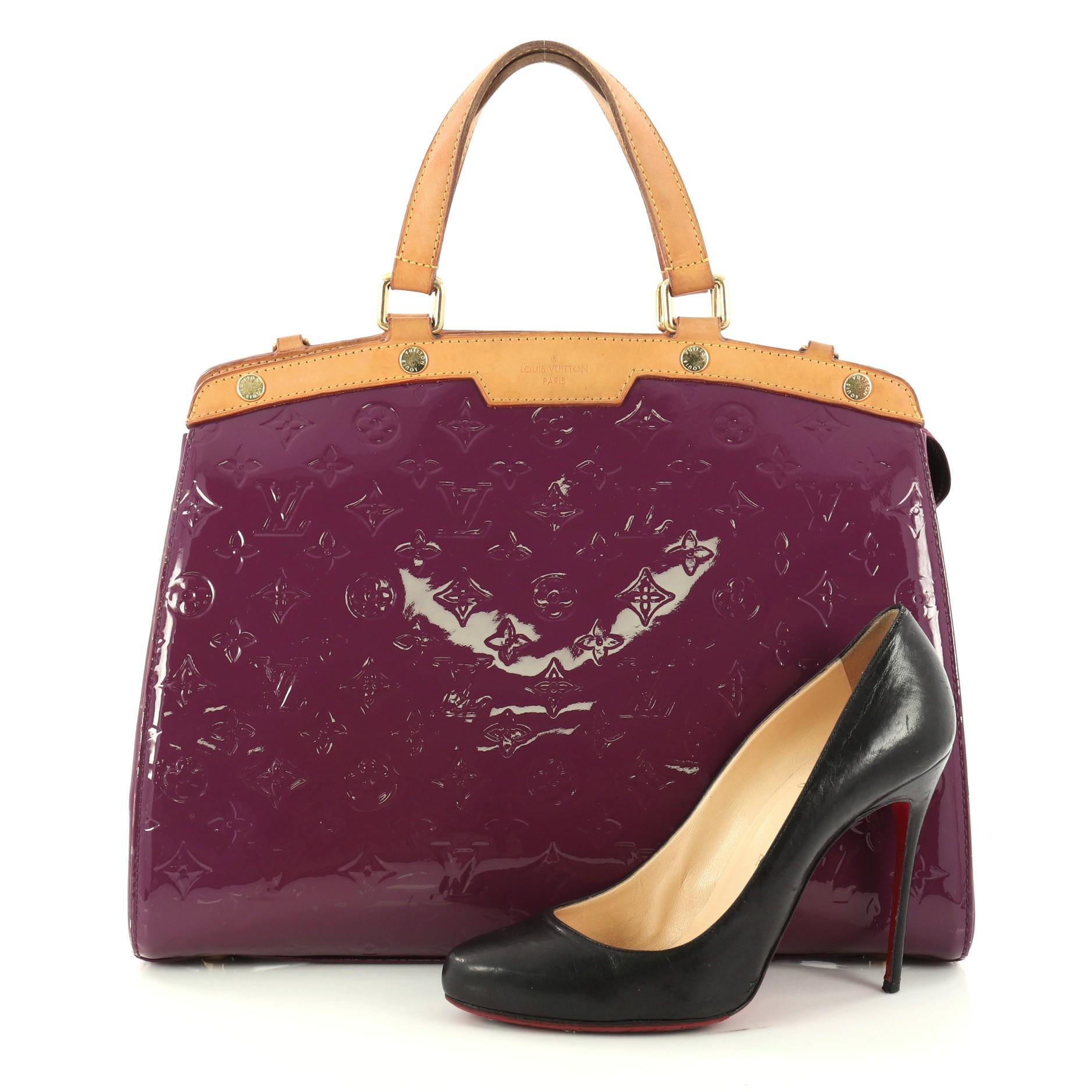 This authentic Louis Vuitton Brea Handbag Monogram Vernis GM is a staple for an everyday casual look. Crafted in purple monogram vernis leather with cowhide leather trims, this structured yet feminine tote features dual flat handles, protective base
