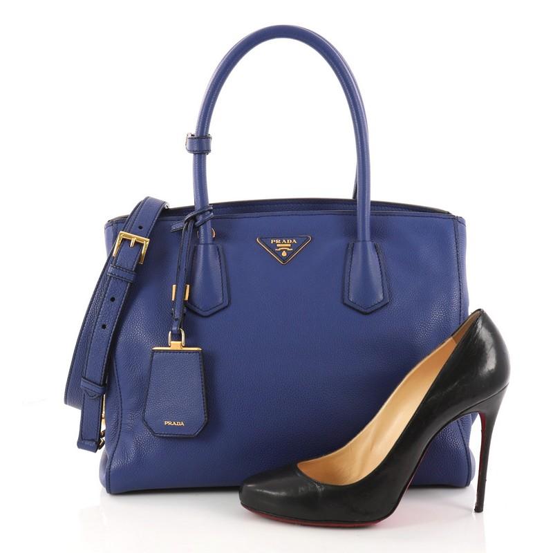 This authentic Prada Convertible Open Tote Vitello Daino Medium is a simple yet luxurious bag perfect for everyday use. Crafted in blue vitello daino leather, this chic-casual tote features a signature Prada logo at the center, dual-rolled leather
