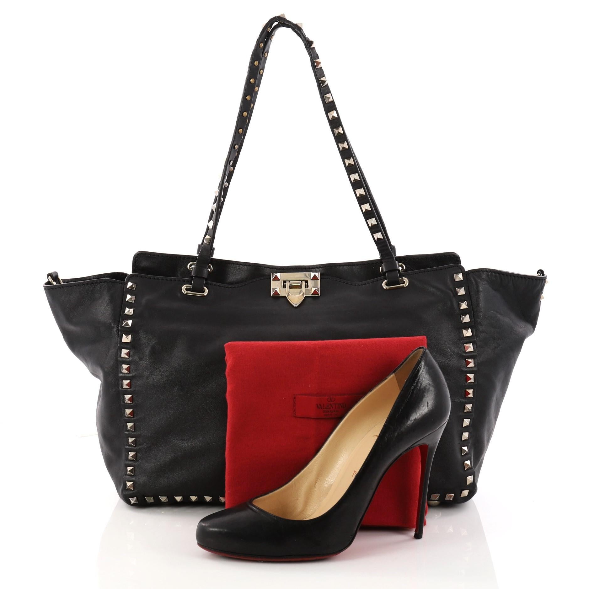 This authentic Valentino Rockstud Tote Soft Leather Medium mixes edgy style with luxurious detailing. Crafted from black soft leather, this stylish tote features dual tall flat handles, gold-tone pyramid stud trim details, signature clasp lock,