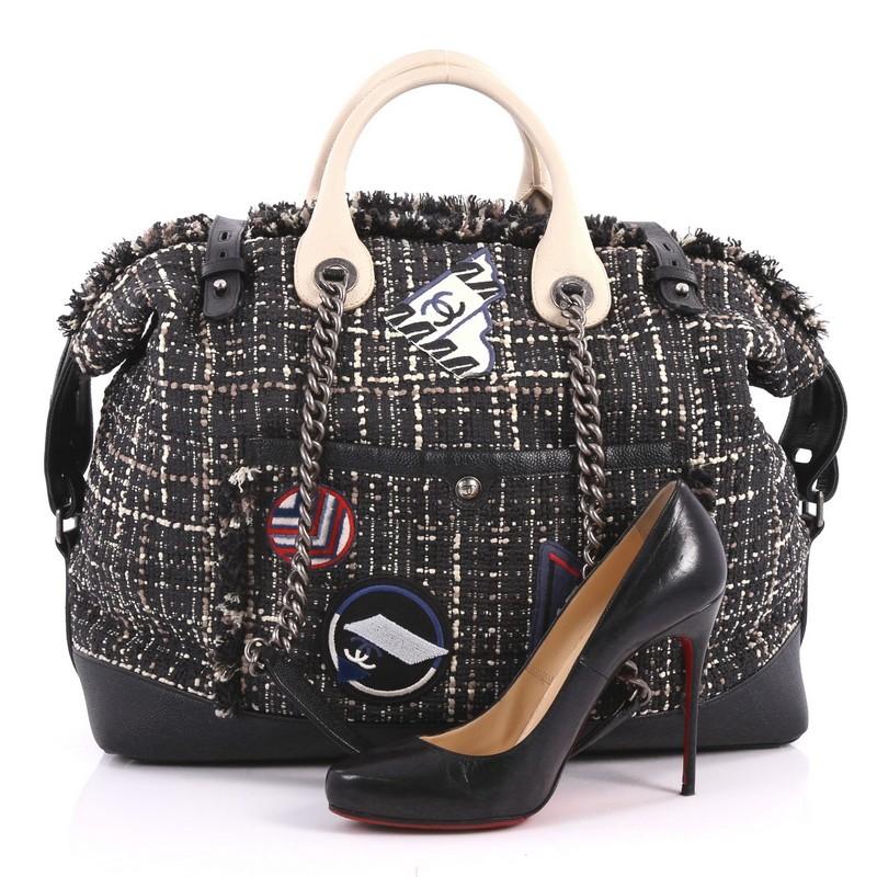 This authentic Chanel Crest Trip Bowling Bag Patch Embellished Tweed and Grained Calfskin Large is a luxurious travel piece to glam up your casual look. Crafted in black tweed with black grained calfskin leather trims, this stand-out piece features