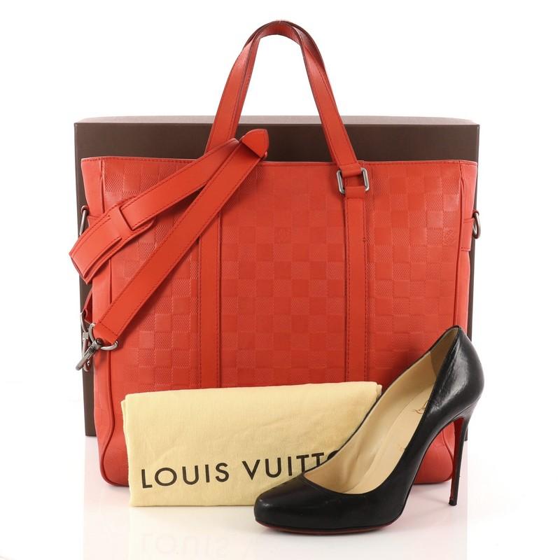 This authentic Louis Vuitton Tadao Handbag Damier Infini Leather PM is a highly versatile and sophisticated tote made for the style-conscious professional. Crafted from red damier infini leather, this luxurious on-the-go tote features dual-flat