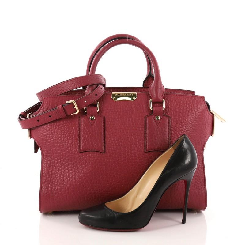 This authentic Burberry Clifton Convertible Tote Heritage Grained Leather Medium is a chic and stylish bag. Crafted from red grained leather, this bag features dual-rolled leather handles, detachable strap, buckled side closures, protective base