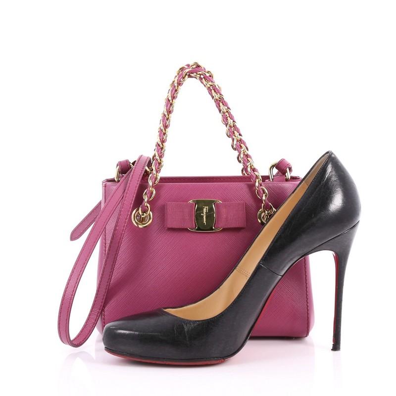 This authentic Salvatore Ferragamo Melike Tote Saffiano Leather Mini gives a casual twist to its usual brand's style. Crafted in fuchsia saffiano leather, this tote features dual woven-in leather chain link straps, detachable strap, signature