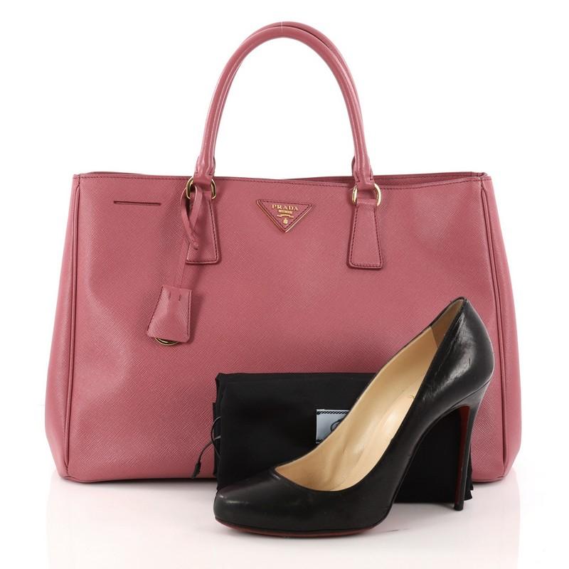 This authentic Prada Lux Open Tote Saffiano Leather Large is elegant in its simplicity and structure. Crafted from pink saffiano leather, this sturdy and spacious tote features dual-rolled handles, gusseted side with snap buttons, iconic Prada logo