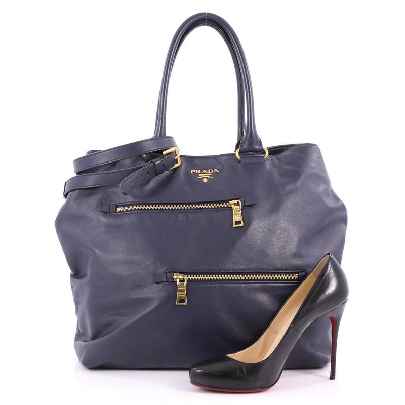 This authentic Prada Convertible Zipper Detail Tote Soft Calfskin Large exudes a stylish and industrial design made for on-the-go woman. Crafted from navy soft calfskin leather, this exquisite bag features dual-rolled handles, raised Prada Milano