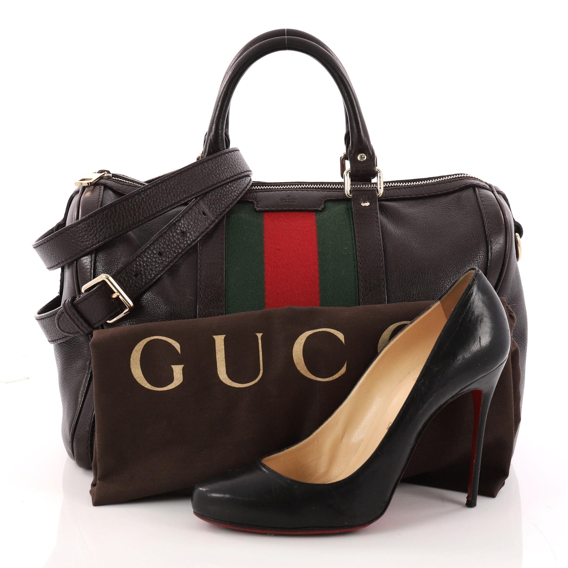 This authentic Gucci Vintage Web Boston Bag Leather Medium is a recognizable classic. Crafted from black leather with signature green and red web stripes, this bag features dual-rolled handles, protective base studs, and gold-tone hardware accents.