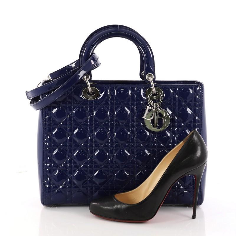 This authentic Christian Dior Lady Dior Handbag Cannage Quilt Patent Large is a classic staple that every fashionista needs in her wardrobe. Crafted from blue patent leather in Dior's iconic cannage quilting, this boxy bag features dual-rolled