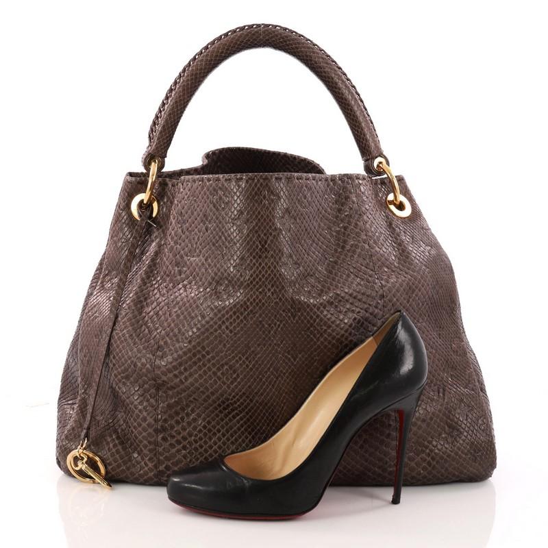 This authentic Louis Vuitton Artsy Handbag Monogram Embossed Python MM is as elegant as it is sturdy. Crafted from genuine dark taupe monogram embossed python skin, this luxurious and refined hobo features a single looped handle with polished gold