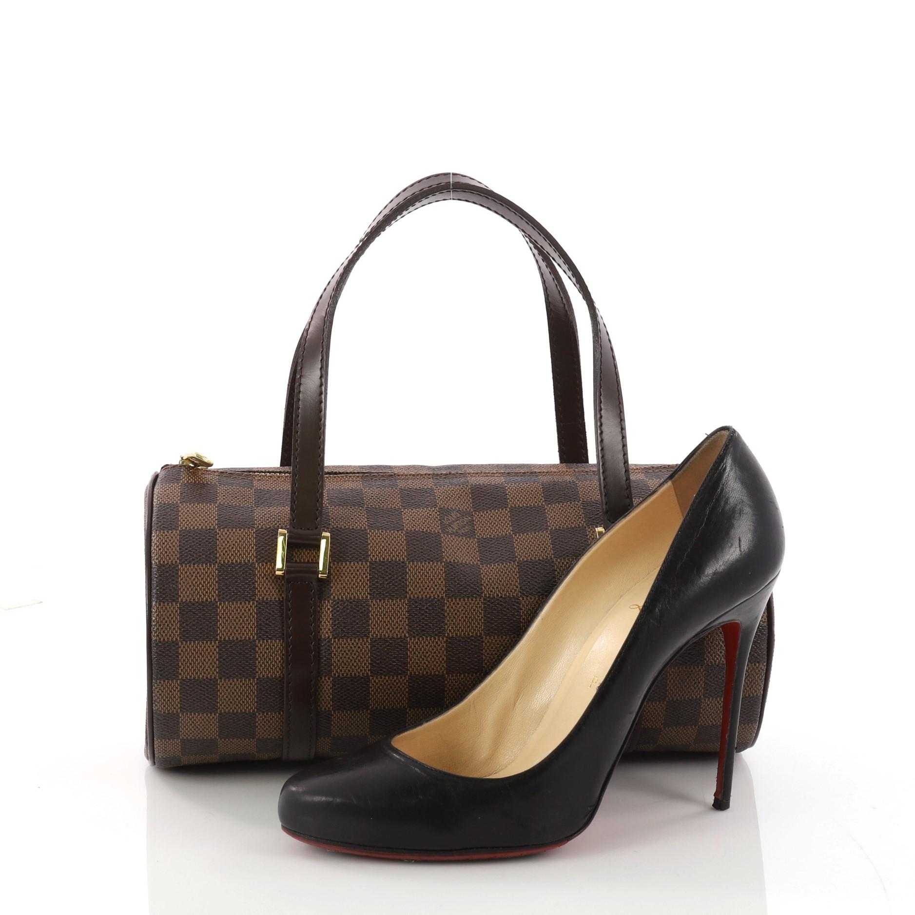 This authentic Louis Vuitton Papillon Handbag Damier 26 is one of Louis Vuitton's iconic bags with its unique round shape that complements both dressy and casual looks. Crafted with damier ebene coated canvas, this practical handle bag features dark