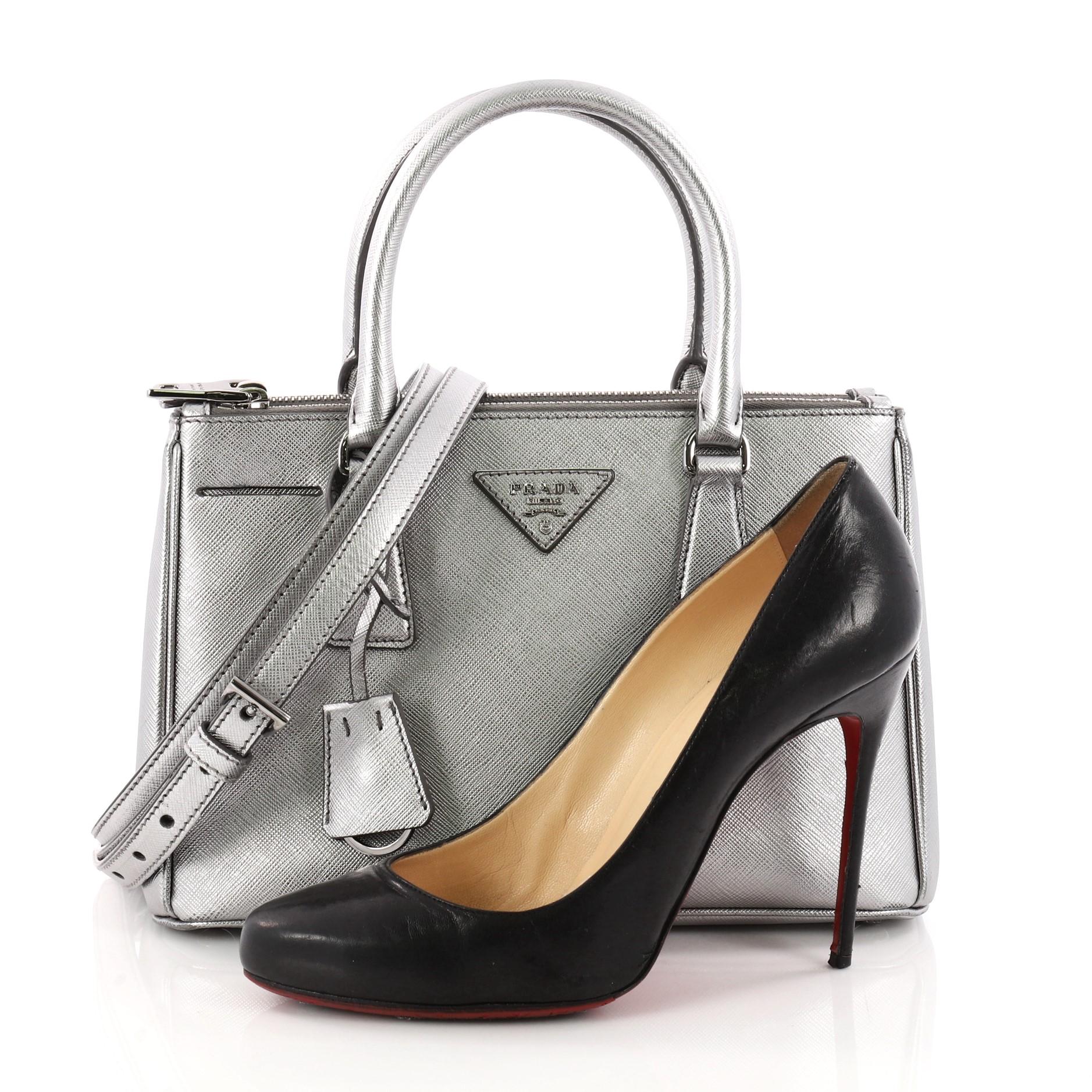 This authentic Prada Double Zip Lux Tote Saffiano Leather Mini is the perfect bag to complete any outfit. Crafted from metallic silver saffiano leather, this boxy tote features side snap buttons, raised Prada logo, dual-rolled leather handles and