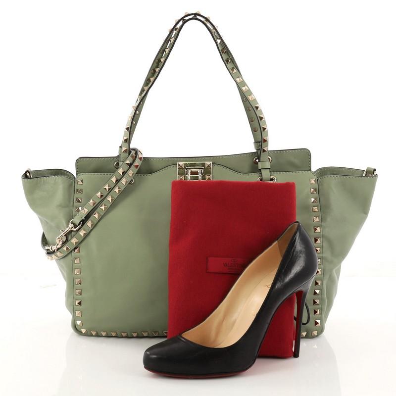 This authentic Valentino Rockstud Tote Soft Leather Medium mixes edgy style with luxurious detailing. Crafted from light green soft leather, this stylish tote features dual tall flat handles, gold-tone pyramid stud trim details, signature clasp