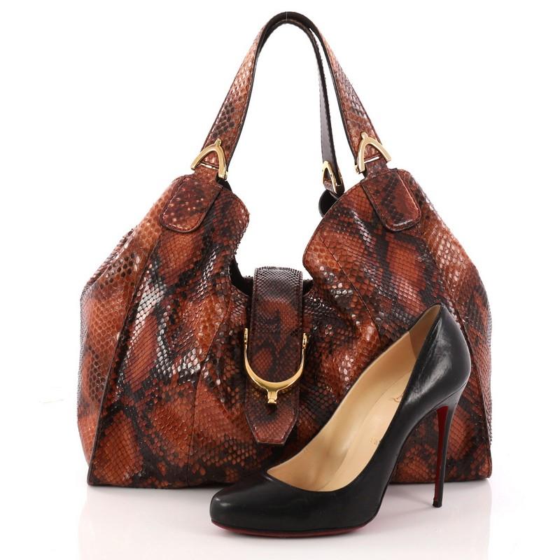 This authentic Gucci Soft Stirrup Tote Python Medium in luxurious and sleek design is made for all seasons. Crafted from genuine brown python skin, this exotic hobo-style shoulder bag features side to side looped dual-flat handles with unique spur