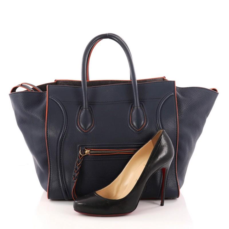 This authentic Celine Phantom Handbag Grainy Leather Medium is one of the most sought-after bags beloved by fashionistas. Crafted from navy blue grainy leather, this minimalist tote features dual-rolled handles, an exterior front pocket, protective