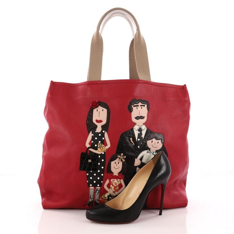 This authentic Dolce & Gabbana Open Tote Patchwork Leather Large is one of the cutest pieces of accessory you'll ever see. Crafted in red leather embellished with a family portrait, this adorable tote features dual top handles and gold-tone hardware