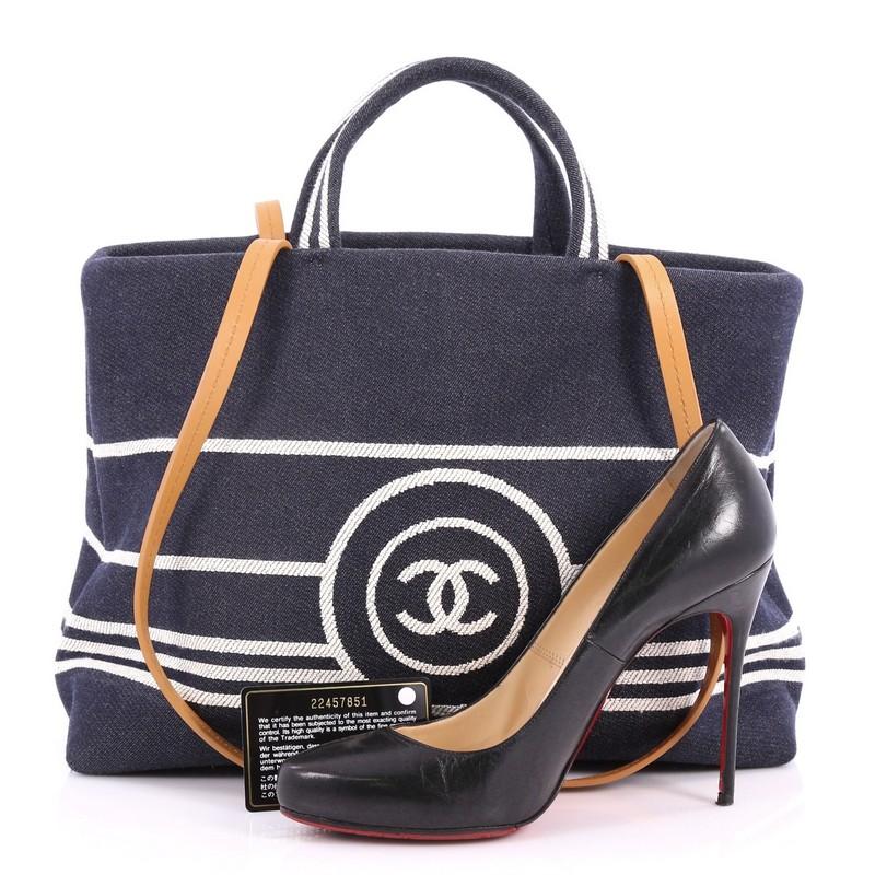 This authentic Chanel CC Shopping Tote Denim Large is ideal for everyday use. Crafted in blue denim, this tote features dual top flat denim handles with long leather shoulder straps, CC printed logo in front and silver-tone hardware accents. It wide