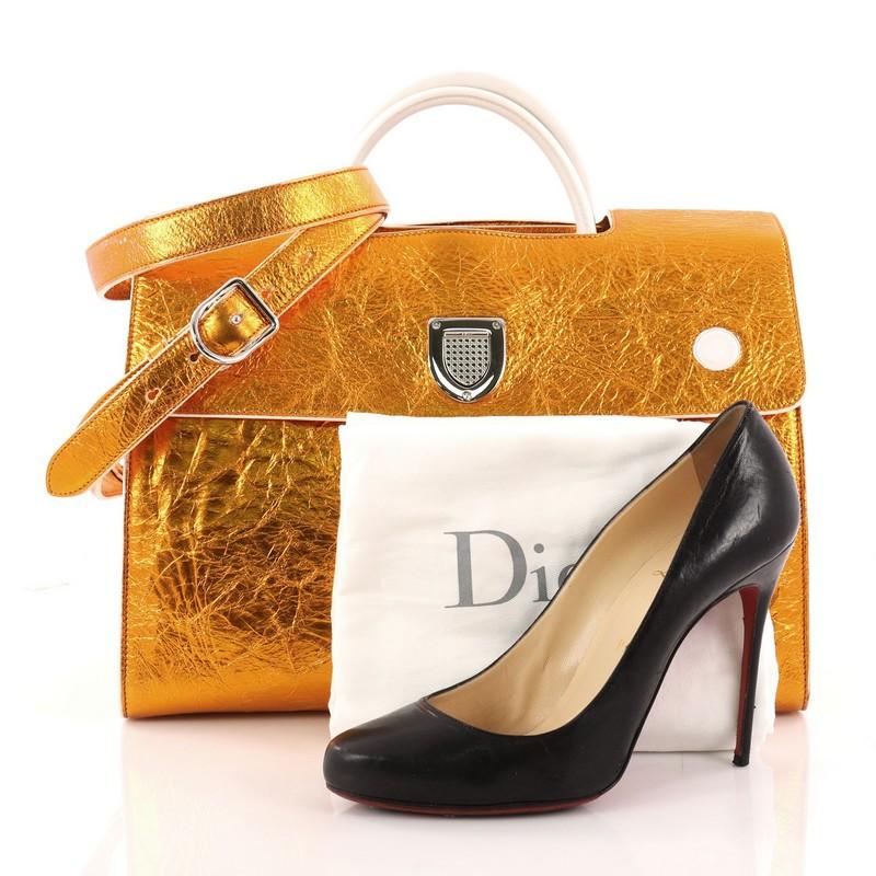 This authentic Christian Dior Diorever Handbag Metallic Leather Large is a bold city tote, with a youthful and sporty motif. Crafted in orange metallic leather, this bag features a reversible flap, unique crest-shaped clasp, dual-rolled leather