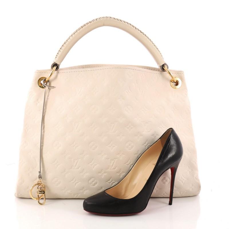 This authentic Louis Vuitton Artsy Handbag Monogram Empreinte Leather MM is an iconic hobo. Crafted from off white monogram embossed empreinte leather, this hobo features a single looped braided top handle with polished gold links, protective base