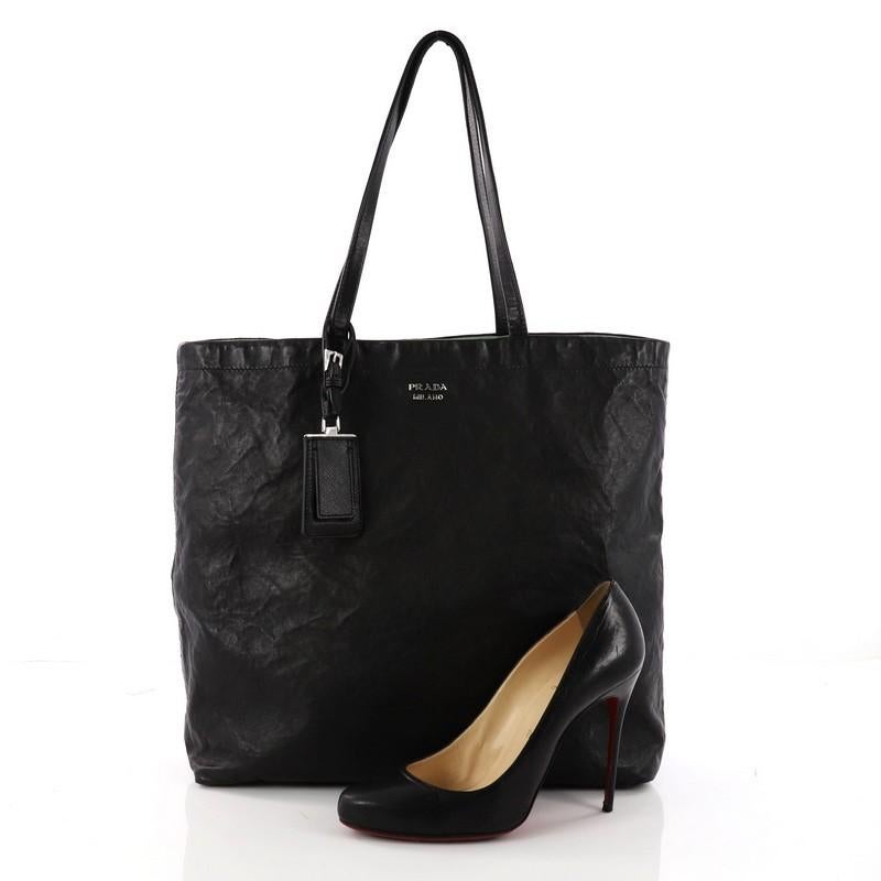This authentic Prada Reversible Tote Soft Calfskin Large is ideal for the on-the-go care-free individual. Crafted from black calfskin leather, this reversible, functional tote features dual-slim leather handles, and silver-tone hardware accents. It