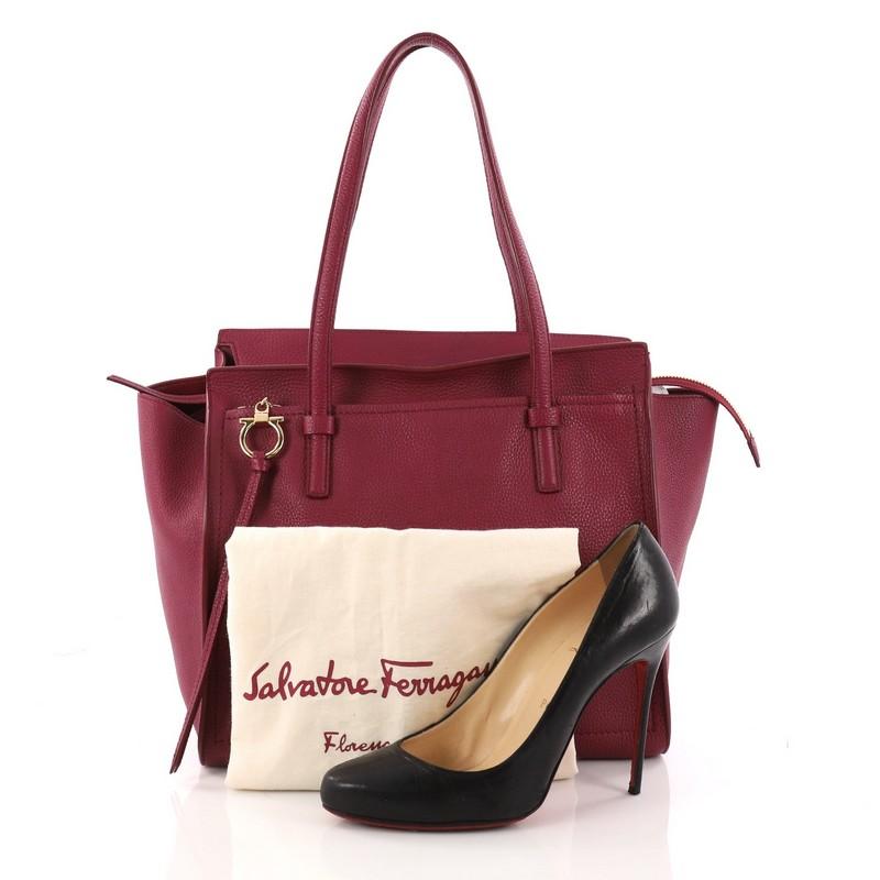 This authentic Salvatore Ferragamo Amy Tote Pebbled Leather Medium is a spacious everyday bag. Crafted from red pebbled leather, this timeless tote features dual flat shoulder strap, exterior front zip pocket with Gancio charm zip pull, Salvatore