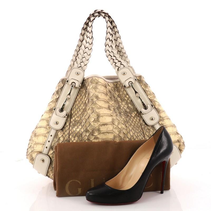 This authentic Gucci Pelham Shoulder Bag Python Medium is a stylish bag perfect for everyday use. Crafted in genuine light gold python skin, this shoulder bag features braided leather straps, signature horsebit detailing, protective base studs, and