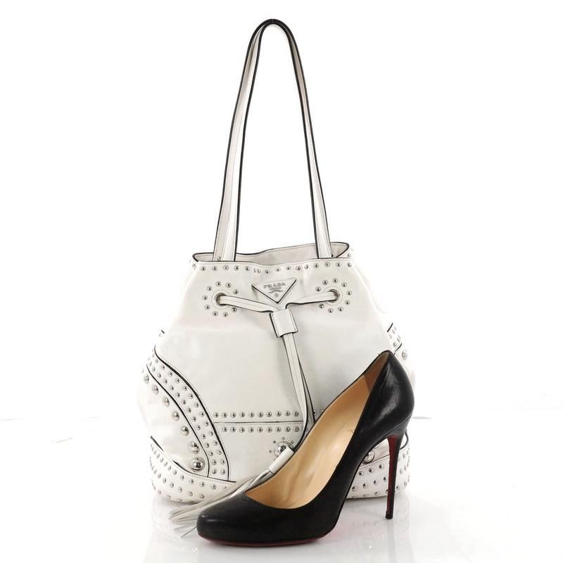 This authentic Prada Bucket Bag Studded Soft Calfskin Large is a classic bucket bag shape with modern minimalist touches that we love. Crafted in white studded soft calfskin leather, this bag features flat leather shoulder strap, an adjustable