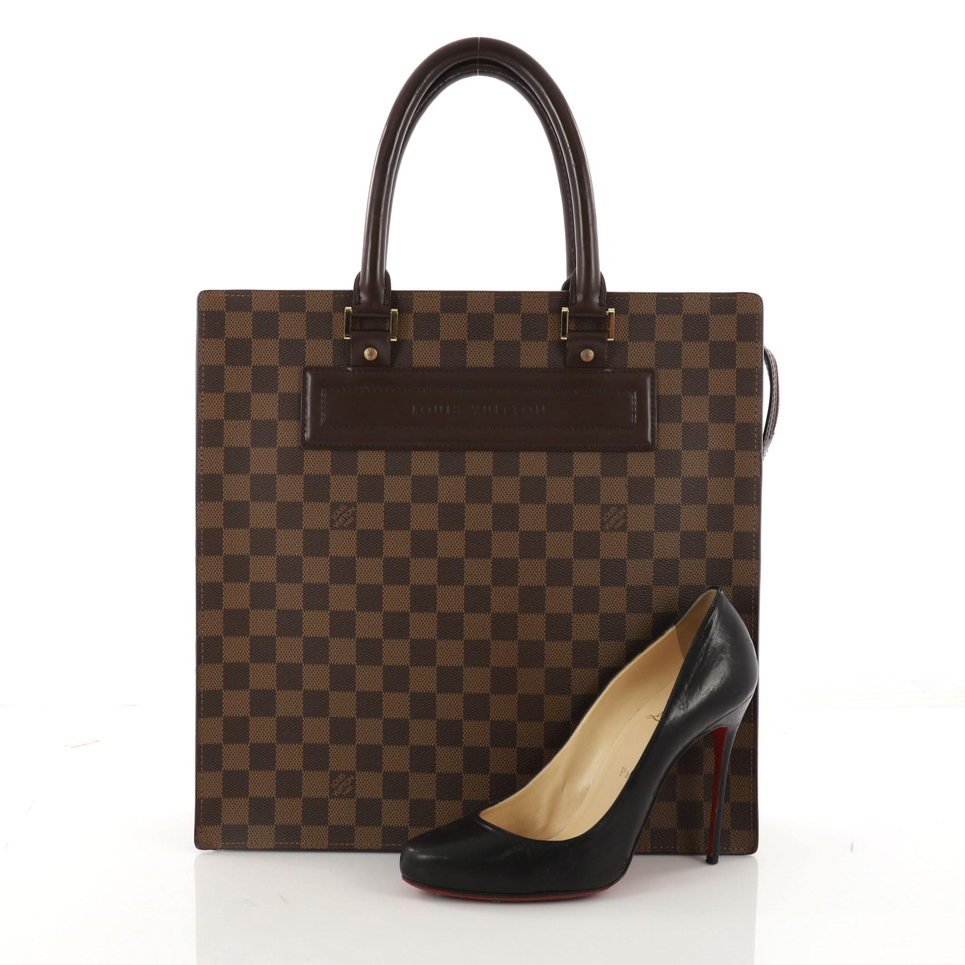 This authentic Louis Vuitton Venice Sac Plat Handbag Damier GM is a compact and structured design perfect for your work essentials. Crafted in the iconic damier ebene coated canvas, this simple bag features dual-rolled leather handles, gusseted