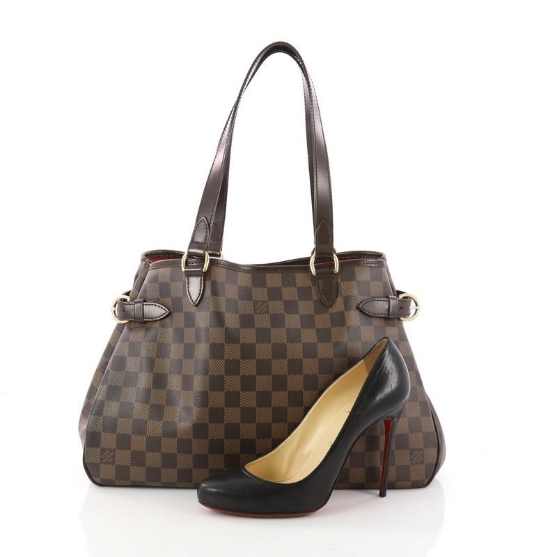 This authentic Louis Vuitton Batignolles Handbag Damier Horizontal is a classic accessory made for casual wear. Crafted from Louis Vuitton's damier ebene coated canvas, this functional tote features dark brown leather shoulder straps and trims,