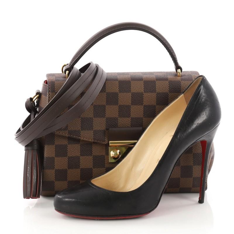 This authentic Louis Vuitton Croisette Handbag Damier is a marvelous bag ideal for everyday convenience. Crafted in damier ebene coated canvas, this stylish bag features dark brown leather top handle and gold-tone hardware accents. It opens to a red