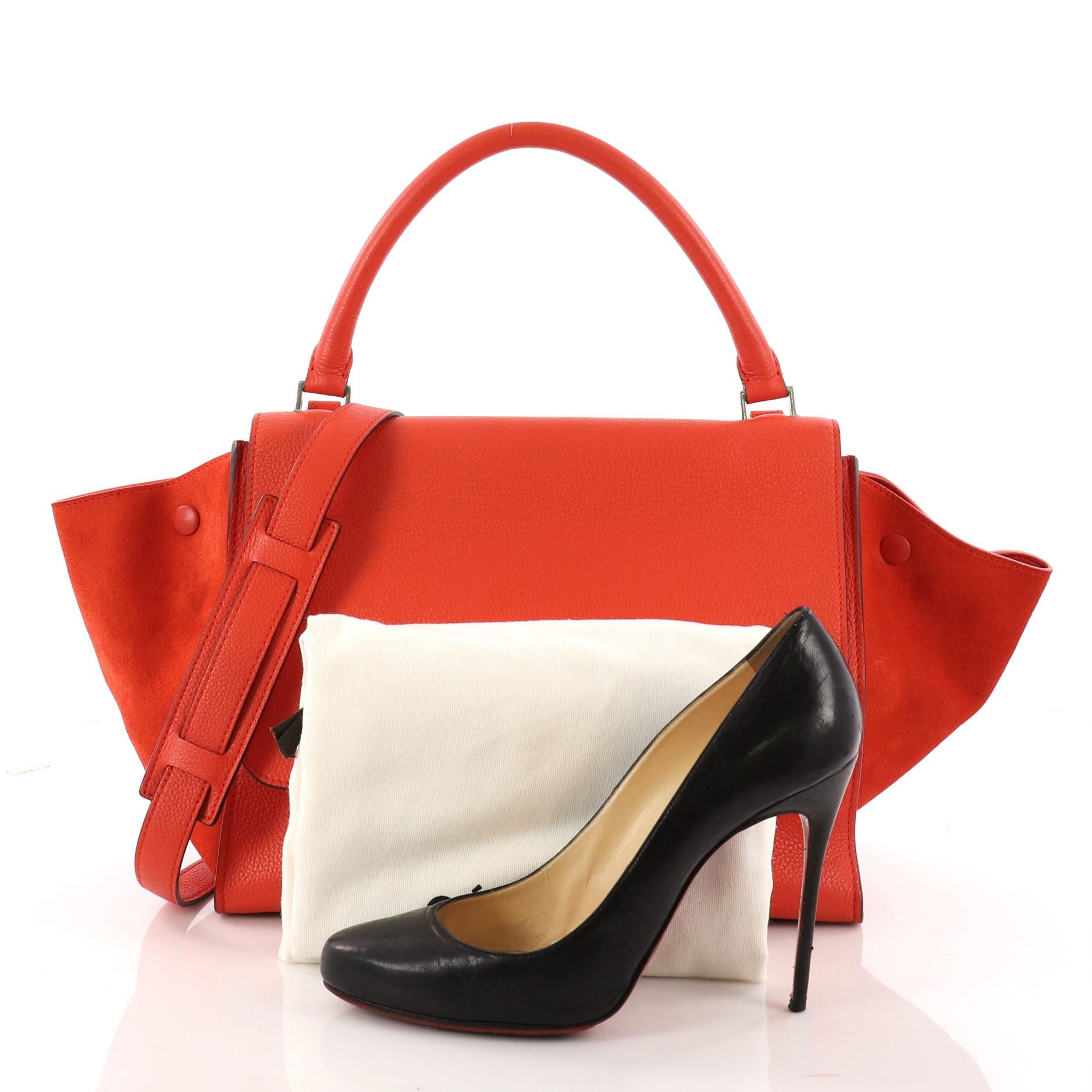 This authentic Celine Trapeze Handbag Leather Medium is a modern minimalist design with a playful twist in an array of subdued colors. Crafted from red leather, this popular bag features exterior back zip pocket, side snap closures, top looped