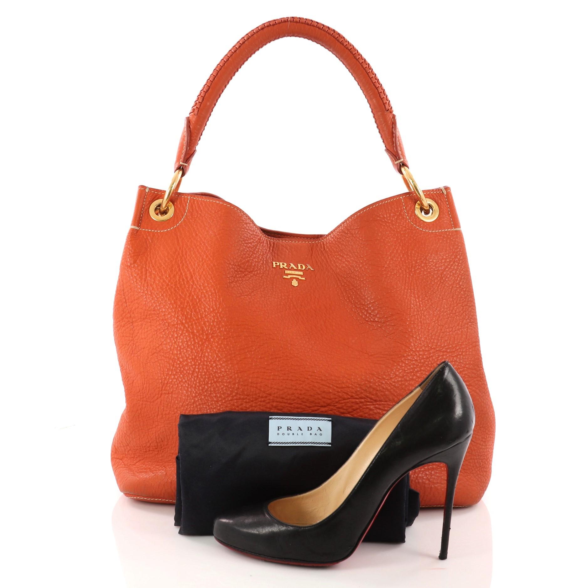 This authentic Prada Rolled Hobo Vitello Daino Large is great for comfort and style. Crafted from orange vitello daino leather, this slouchy no-fuss hobo features a rolled shoulder strap, gold hardware accents and Prada nameplate rests on the face