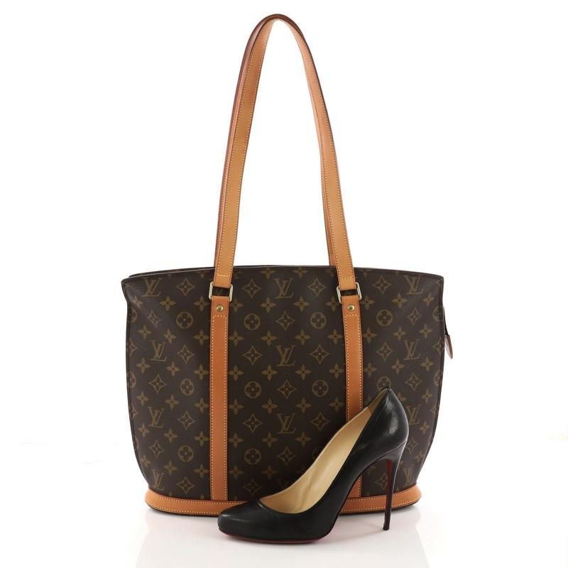 This authentic Louis Vuitton Babylone Handbag Monogram Canvas is a stylish and durable tote that is ideal for everyday use. Crafted from brown monogram coated canvas, this bag features natural vachetta cowhide leather straps and trims, gold-tone