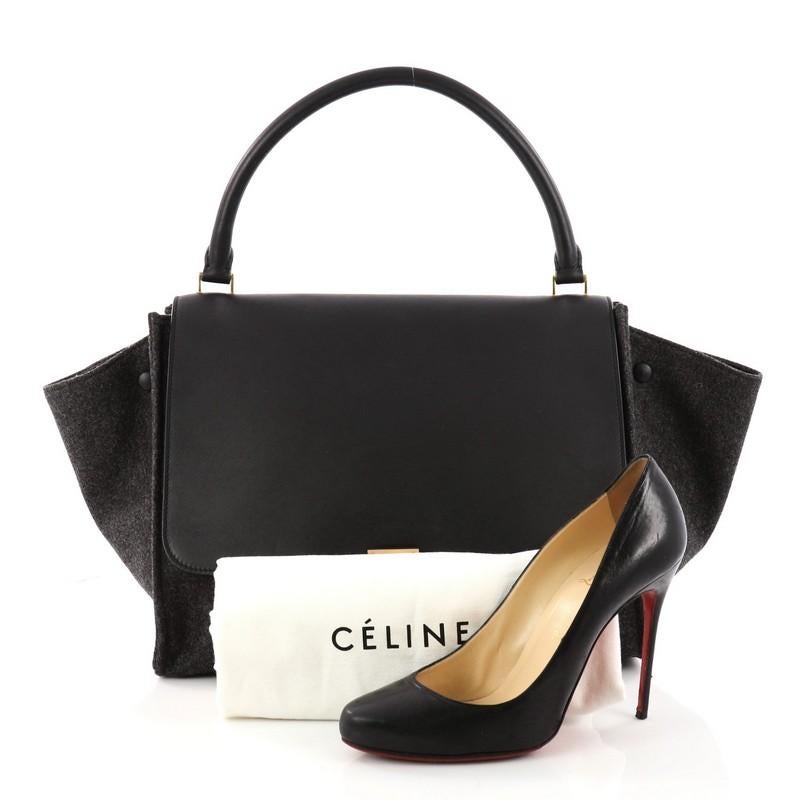 This authentic Celine Trapeze Handbag Leather and Felt Medium is every fashionista's dream. Crafted in black leather and gray felt, this classic bag features a top handle, exterior back pocket and gold-tone hardware accents. Its square flip-lock