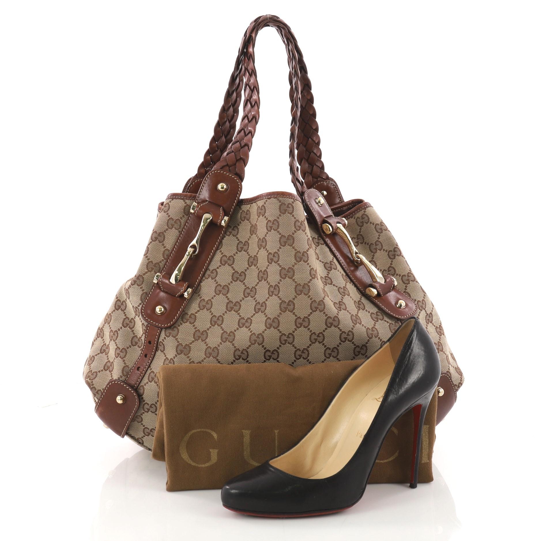 This authentic Gucci Pelham Shoulder Bag GG Canvas Medium is a stylish bag perfect for everyday use. Crafted in light brown GG monogram canvas with brown leather trims, this shoulder bag features braided leather straps, signature horsebit detailing,