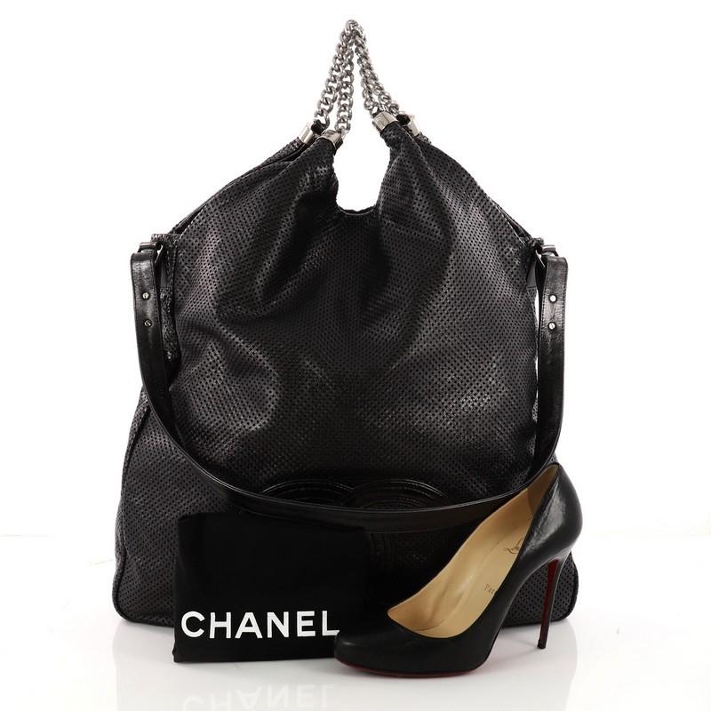 This authentic Chanel Rodeo Drive Hobo Perforated Leather Large is a casual, care-free bag made for the modern woman. Crafted from black perforated leather, this tote features dual chunky silver chain-link handle straps, leather shoulder strap,