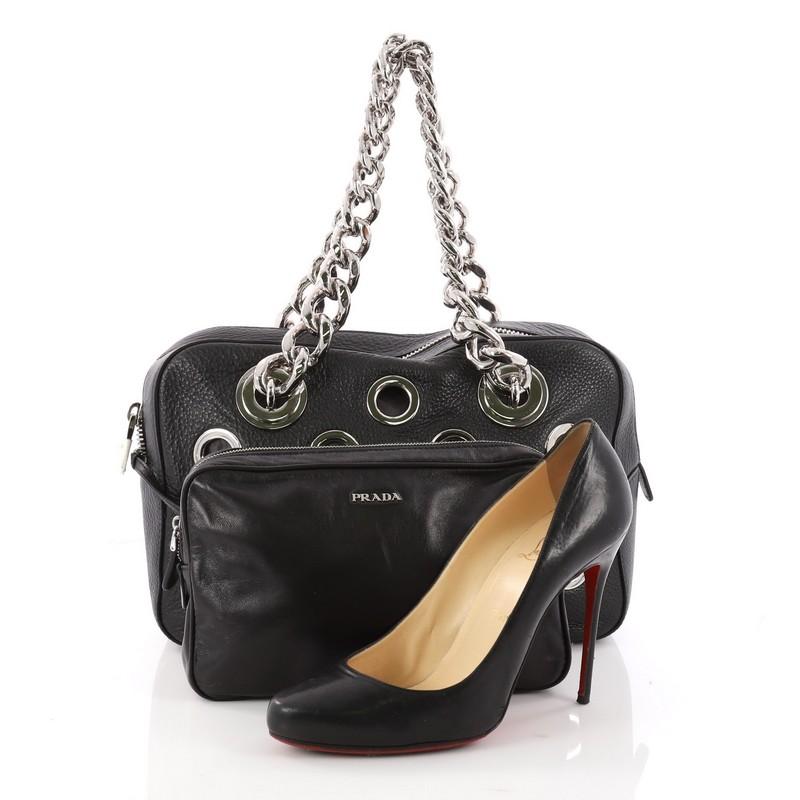 This authentic Prada Grommet Chain Shoulder Bag Vitello Daino Medium is a gorgeous shoulder bag perfect for your day or evening looks. Crafted from black vitello daino leather, this chic bag features dual chunky silver chain straps, large grommets